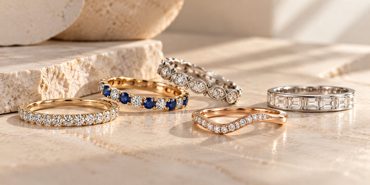 Curated collection of five luxury wedding bands featuring diamond, sapphire, vintage, curved, and baguette designs on a warm stone surface.