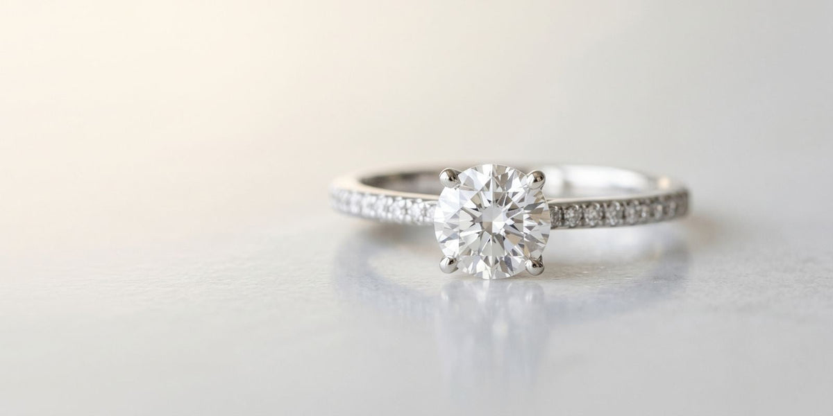 Close-up of an affordable lab grown diamond promise ring with an oval center stone and pavé band on a soft neutral background.