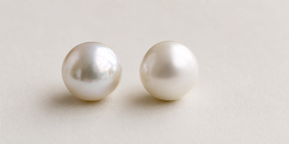 Two white pearls under matching lighting, with the left pearl showing crisp high luster and the right showing softer, weaker reflections.