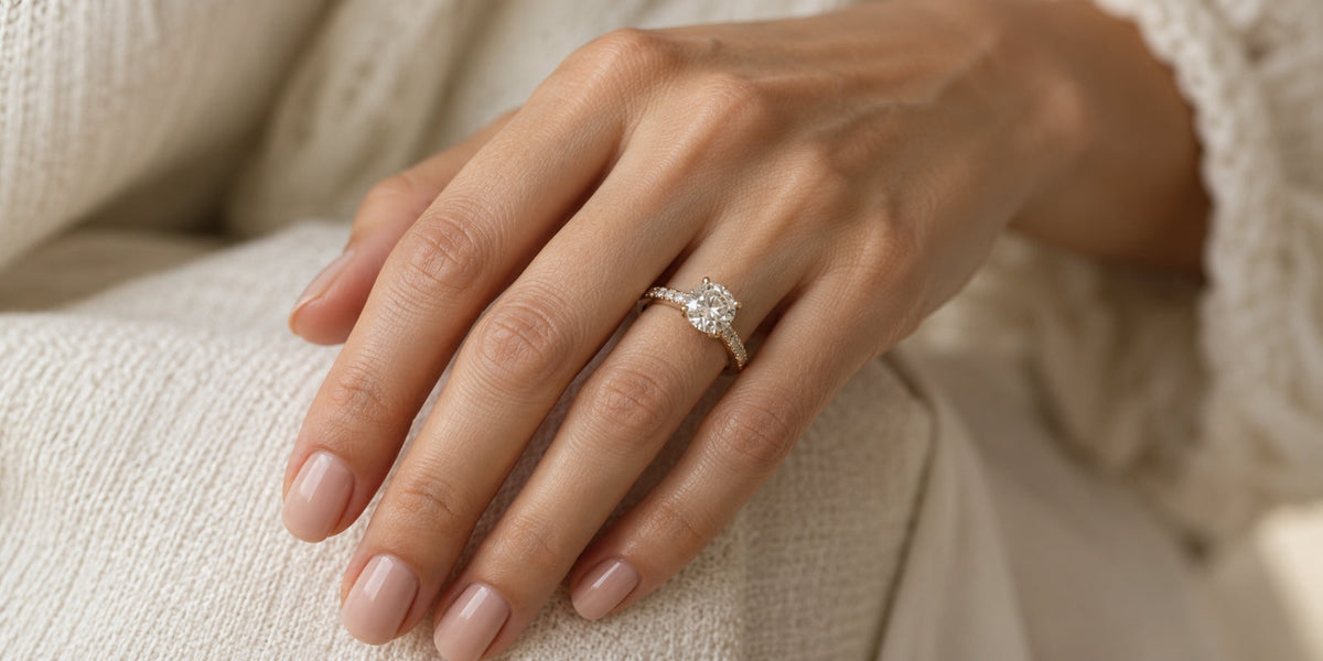 Woman’s hand wearing a coordinated diamond engagement ring and wedding bands in an elegant bridal stack.